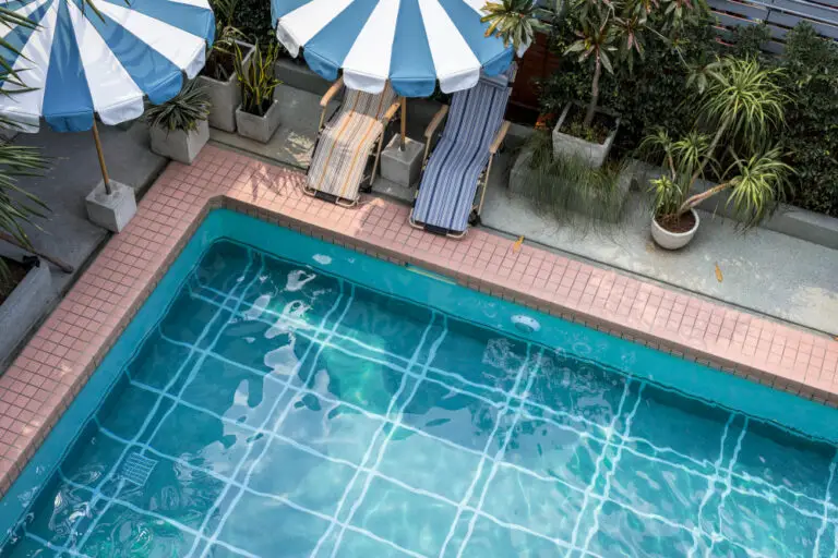 Aerial view of a swimming pool with clear blue water, surrounded by pink tiles.
